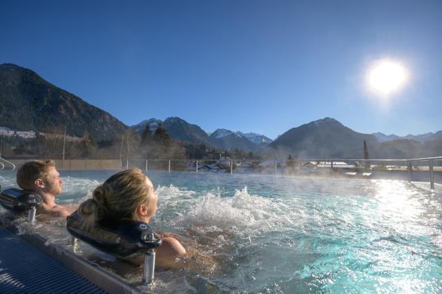 Infinity-Pool auf der Dachterrasse mit Besuchern, Liegen und Blick auf die Berge