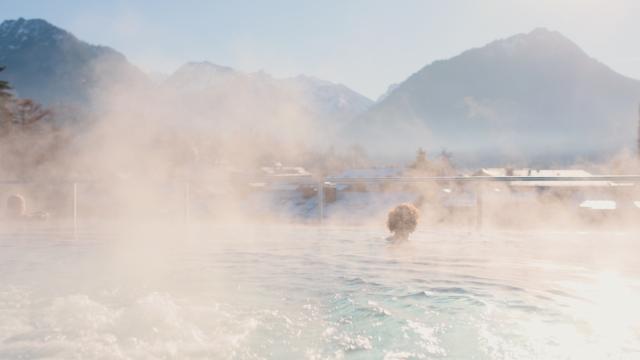 Infinity-Pool auf der Dachterrasse mit Besuchern, Liegen und Blick auf die Berge